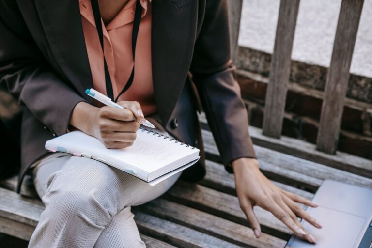 Person writing notes in a notebook, seen from above, illustrative photo